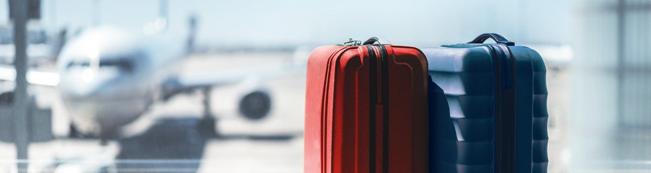 Koffer im Vordergrund ein Flugzeug im Hintergrund