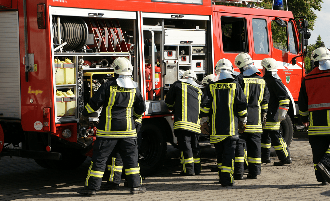 Fire brigade in front of a fire truck, checking the equipment
